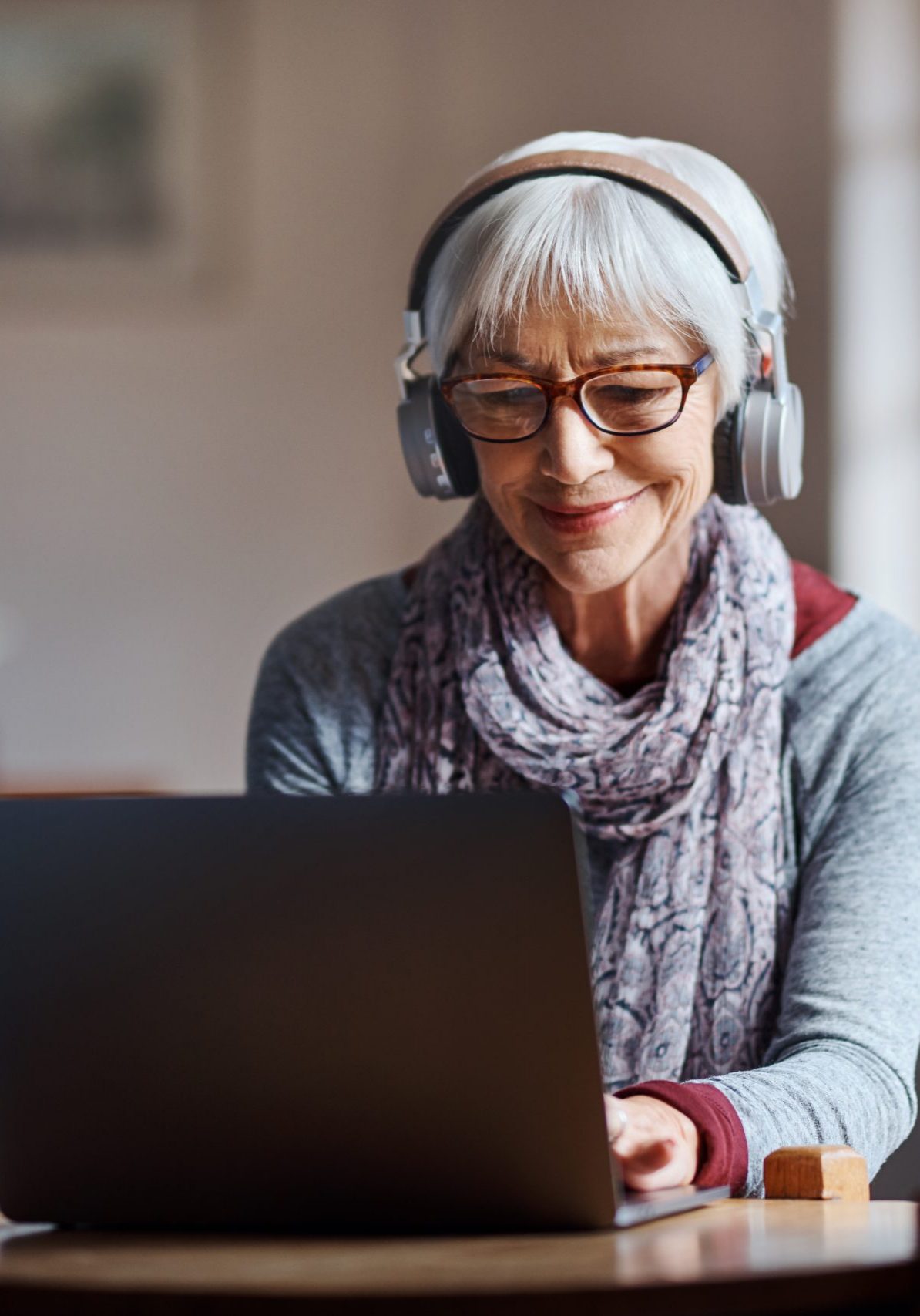 Shot of a senior woman using a laptop and headphones in a retirement home